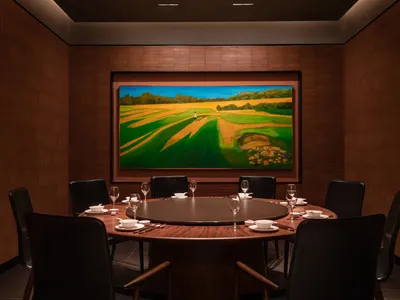 Circular dining table surrounded by black chairs, set with dinnerware and glasses in a modern restaurant dining room with woo
