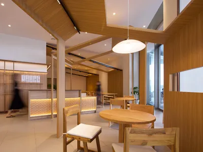 A modern restaurant interior with wooden tables, chairs, and lighting fixtures.
