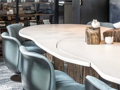 Modern interior design featuring a circular dining table with concrete legs and blue leather chairs, illuminated by contempor