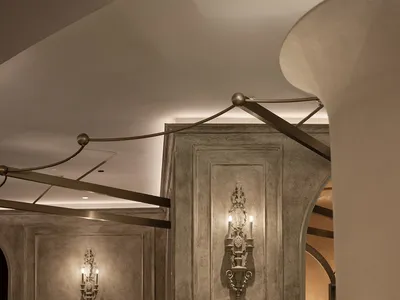 A modern restaurant with a concrete floor and stone walls, featuring elegant sconce lighting.