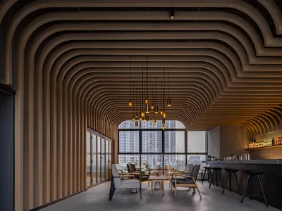 Modern restaurant interior featuring white chairs, dark wood tables, and hanging lights.