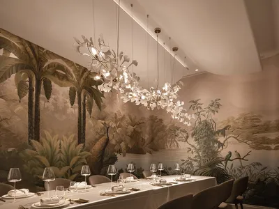 An elegant restaurant dining room with a jungle-themed mural, plush seating, and elaborate lighting fixtures.