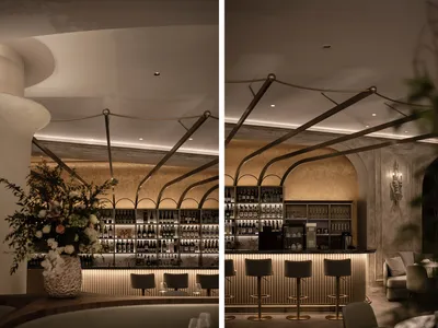A modern restaurant bar interior with metallic stairs and gold-colored lighting.