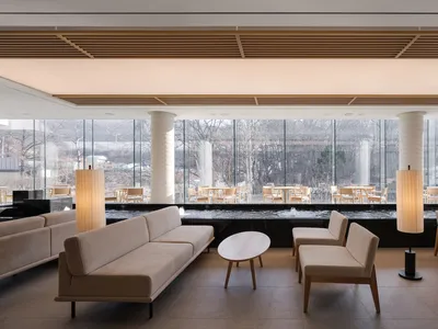 Modern interior design of a restaurant featuring glass walls and concrete flooring.