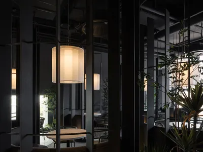An interior view of a modern restaurant with concrete structures and hanging lamps.
