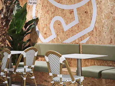 A café interior featuring natural materials, with a sign that says 'Under the tree' and a large tree plant.