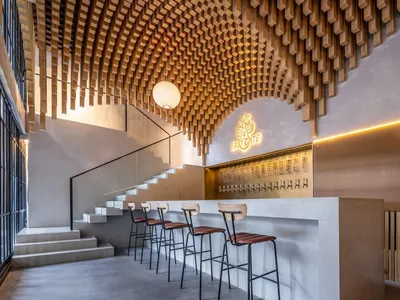 Modern restaurant interior with wooden ceiling, seating area, and signage.