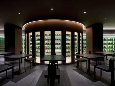Modern minimalist restaurant interior featuring black tables and a sleek, minimalist design with steel and glass materials.
