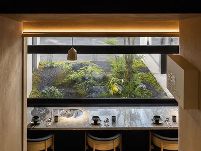 Modern restaurant interior featuring minimalist design with concrete, wood, and stone materials.