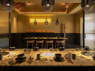 A restaurant interior with marble countertops, wooden beams, and industrial lighting fixtures.