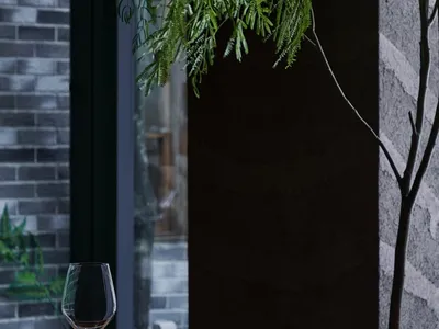 A sleek black dining table with a plant, glassware, and ceramic plates in an industrial-themed restaurant.