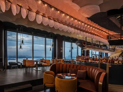 A modern bar restaurant with a leather seating area, ceiling lights, and a view of the water.