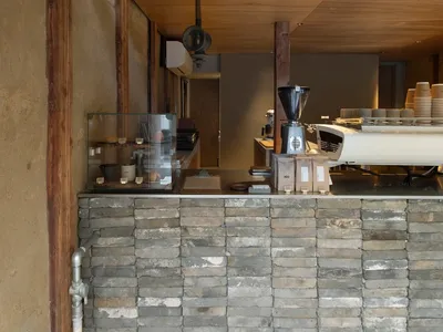 A coffee shop interior with a concrete and wooden counter.