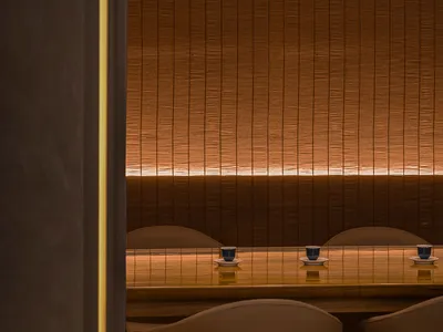 A modern restaurant interior with warm lighting, brown fabric, and wooden furniture.
