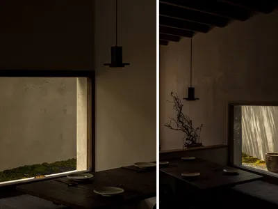 A cozy Asian-themed restaurant space featuring wood and concrete materials, with a low hanging light fixture and a table sett