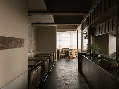 A modern restaurant interior with wooden chairs and concrete flooring.