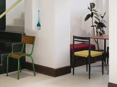 A modern restaurant interior featuring white tiles, wooden benches, and green metal accents.