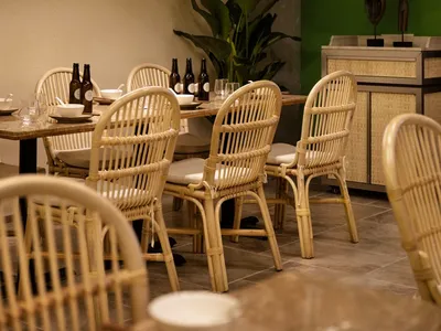 Indoor restaurant dining area with wicker furniture and industrial lighting.
