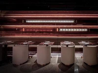 A modern restaurant interior with marble, concrete, and white leather elements.