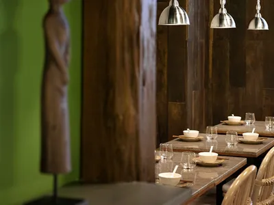 A modern industrial restaurant interior with wooden furniture and metallic pendant lights.