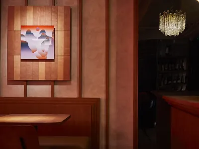 Industrial-style restaurant interior with wooden paneling, abstract art, and crystal chandelier.
