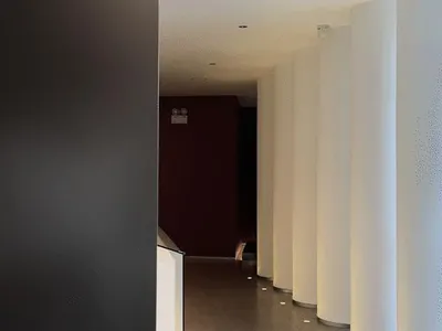 View of a hotel corridor featuring white cylindrical columns and black walls.