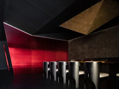 A sleek, modern restaurant interior featuring a glass bar counter with a geometric ceiling design.