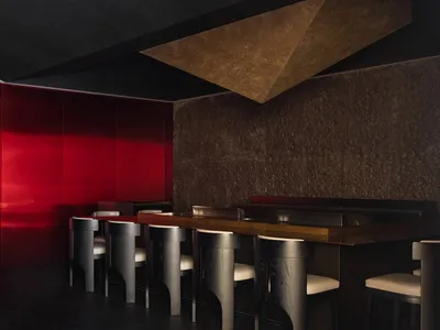 Minimalist restaurant interior featuring a metallic counter and sleek seating.