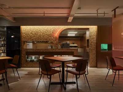 A modern restaurant with stone walls and wooden tables and chairs.