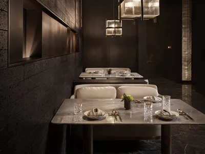 A restaurant interior featuring industrial design elements with dark concrete walls and a dark tile floor.