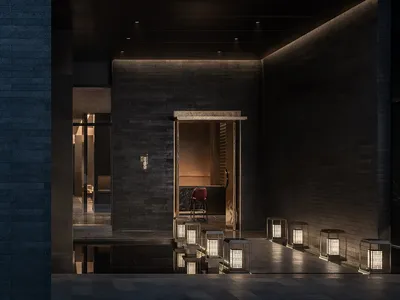 A modern restaurant entryway featuring dark brick walls with a minimalist design.