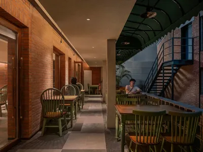 A rustic restaurant interior with exposed brick walls, concrete pillars, and tiled flooring.