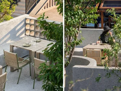 Outdoor seating area with concrete patio, chairs, and greenery in an industrial setting.