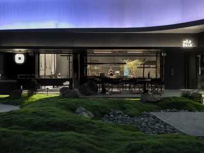 Contemporary restaurant exterior with concrete pavement, grass, and a modern design.