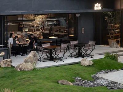 Outdoor seating area of a restaurant with tables and chairs surrounded by greenery.