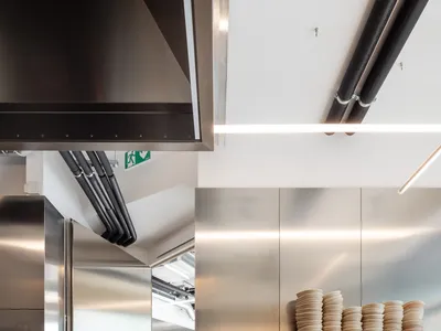 A modern commercial kitchen with stainless steel appliances and countertops, featuring sleek design and efficient layout.