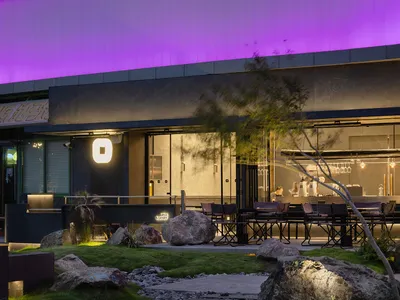 A modern restaurant exterior with concrete elements at night.