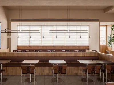 A modern restaurant interior design featuring wooden tables, concrete walls, and leather chairs.
