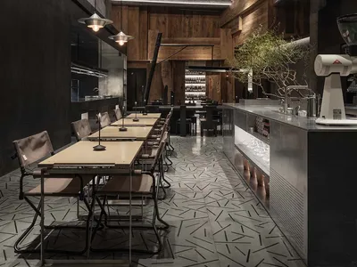 An industrial-style restaurant interior featuring exposed concrete walls and wooden tables.