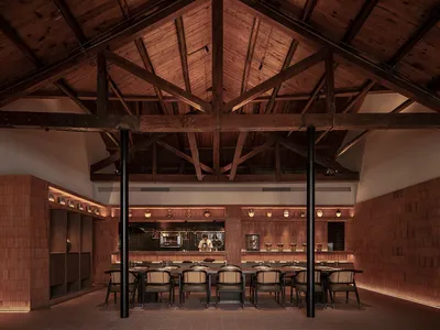 Industrial restaurant interior with wooden beams and tables.