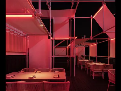 Nighttime view of a restaurant interior with metallic frame scaffolding structures.