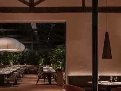 A minimalist restaurant interior featuring glass walls and contemporary design elements.