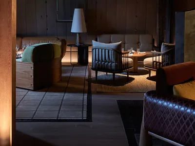 A cozy, industrial-style living room with wooden beams, dark wood furniture, and soft lighting features a comfortable seating