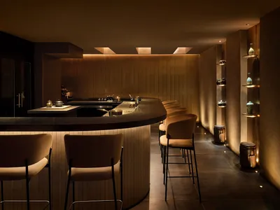 Modern restaurant bar interior with wooden materials and warm lighting.