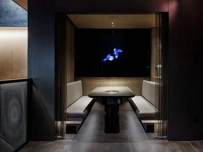 A modern restaurant booth with white leather upholstery and a black table with a central air vent.