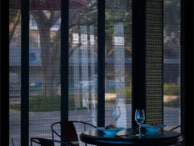 A modern restaurant interior with glass walls, a table, and chairs.