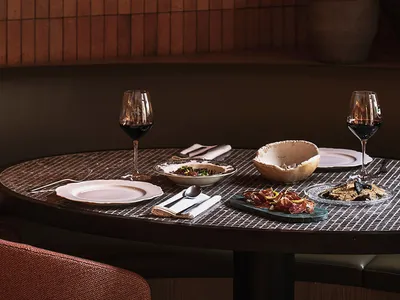 Modern dining room with terracotta tile walls, dark wooden table, and wine glasses.