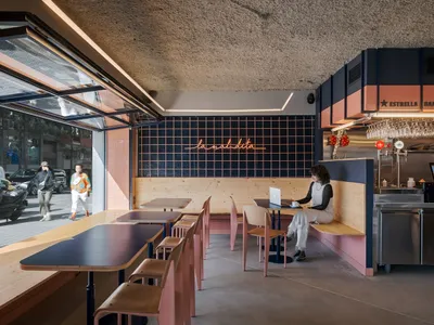 Cafe interior with industrial design featuring concrete tiles, wooden seating, and steel accents.