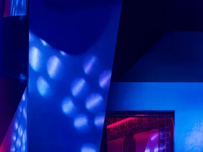 Modern hotel suite featuring metallic-patterned walls illuminated by blue lighting.