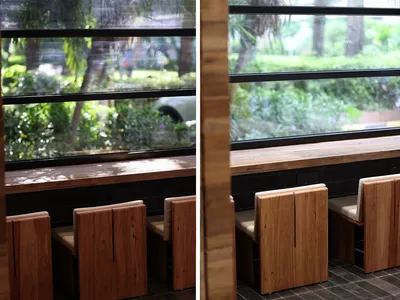 A cozy cafe interior featuring wooden benches and large windows allowing natural light to fill the space.